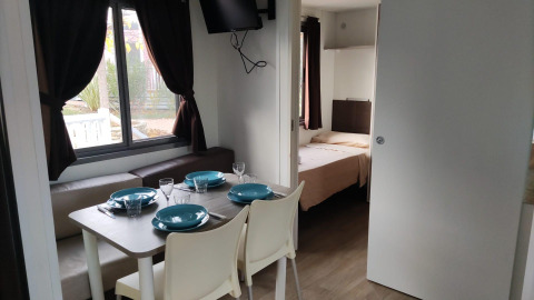 Dining area and bedroom in the Next L Deluxe lodge at Weekend Glamping Resort, Italy, with modern decor.