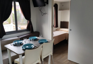 Dining area and bedroom in the Next L Deluxe lodge at Weekend Glamping Resort, Italy, with modern decor.