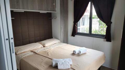 Modern bedroom with double bed, beige linens, window view, Next L Deluxe at Weekend Glamping Resort, Italy