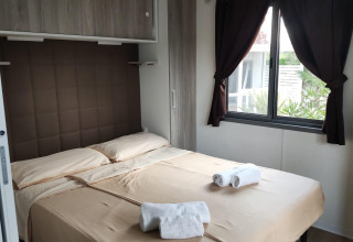 Modern bedroom with double bed, beige linens, window view, Next L Deluxe at Weekend Glamping Resort, Italy