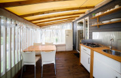 Cuisine et salle à manger lumineuses de glamping Cottage Clever avec sol en bois et mobilier blanc moderne.