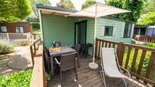 Terrasse extérieure du Cottage Classic Country avec table, chaises, parasol et verdure.