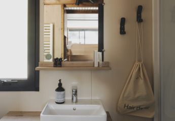 Moderne kleine badkamer met wastafel, spiegel en opbergzak in Tiny Home Family bij Wecamp Jávea, Spanje.