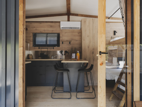 Interieur van TINY HOME FAMILY bij Wecamp Jávea, Spanje met keuken, eethoek en stapelbed in beeld.