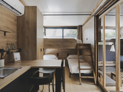 Tiny house interieur met stapelbedden, keuken en eethoek bij Wecamp Jávea in Spanje.
