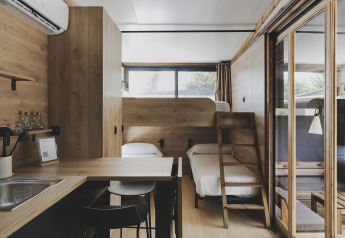 Gezellig tiny house interieur met stapelbedden, keuken en eethoek bij Wecamp Jávea in Spanje.