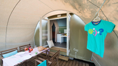 Safari tent Coco Suite op Weekend Glamping Resort Italië met gedekte tafel en een T-shirt aan een hanger.