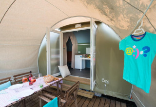 Safari tent Coco Suite op Weekend Glamping Resort Italië met gedekte tafel en een T-shirt aan een hanger.