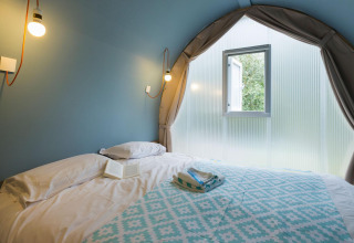 Interieur van een Coco Suite safaritent op Weekend Glamping Resort in Italië, met bed en venster.