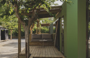 Houten terras bij chalet MOBIL HOME FAMILY op Wecamp Jávea, Spanje, met boom en moderne groene wand.