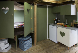 Interieur van safari tent 'Air lodge' met keuken en slaapgedeelte bij Weekend Glamping Resort in Italië.