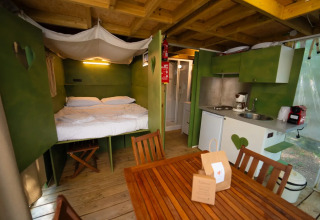 Binnenaanzicht van de safaritent 'Air lodge' bij Weekend Glamping Resort, Italië, met bed en keuken.