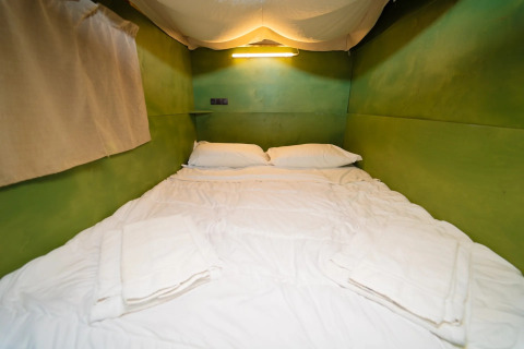 Interieur van de Air Lodge safaritent met groene muren en tweepersoonsbed bij Weekend Glamping Resort, Italië.