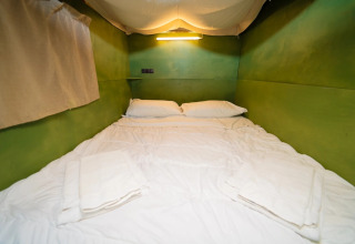 Interieur van de Air Lodge safaritent met groene muren en tweepersoonsbed bij Weekend Glamping Resort, Italië.