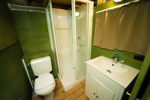 Badkamer in de Air Lodge safaritent op Weekend Glamping Resort in Italië met douche en groene muren.