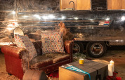 Gemütliche Sitzecke mit Ledersofa, Feuerstelle und Kerzen vor einem Airstream-Tiny House in Chianti Glamping Resort.
