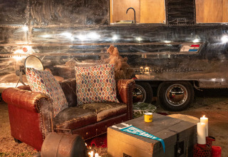 Gezellige zithoek met sofa, vuurkorf en kaarsen voor een Airstream tiny house bij Chianti Glamping Resort.