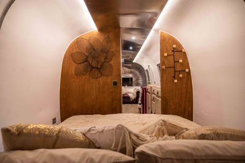 Slaapruimte in de tiny house 'Airstream' bij Chianti Glamping Resort in Italië, met houten details en kussens.