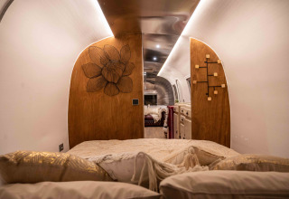 Slaapruimte in de tiny house 'Airstream' bij Chianti Glamping Resort in Italië, met houten details en kussens.