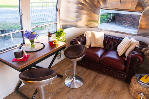 Binnenzicht van een Airstream tiny house in het Chianti Glamping Resort met rode zetel en tafel.