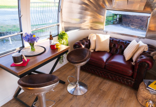 Binnenzicht van een Airstream tiny house in het Chianti Glamping Resort met rode zetel en tafel.