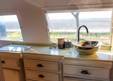 Keuken in een Airstream tiny house op Chianti Glamping Resort in Italië met uitzicht door de ramen.