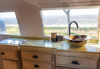 Keuken in een Airstream tiny house op Chianti Glamping Resort in Italië met uitzicht door de ramen.