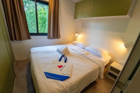Hyggeligt glampingværelse med dobbeltseng, håndklæder, vindue med udsigt og behagelig belysning.