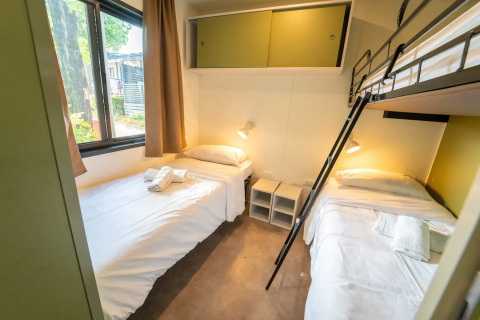 Innenaufnahme einer Glamping-Unterkunft mit drei Betten, Fenster mit Tageslicht und moderner Einrichtung.