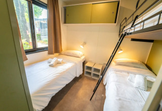 Innenaufnahme einer Glamping-Unterkunft mit drei Betten, Fenster mit Tageslicht und moderner Einrichtung.