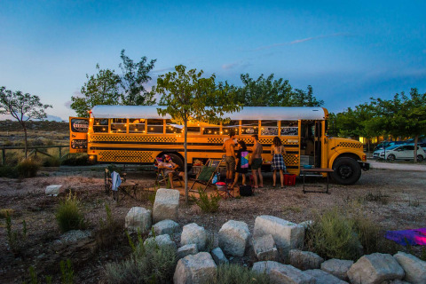 Un tiny house dans un ancien bus scolaire avec des gens au Chianti Glamping Resort en Italie, au crépuscule.