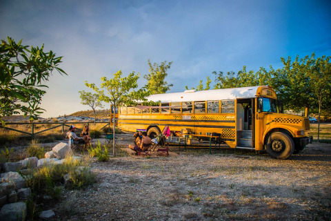 Tiny house dans un ancien bus scolaire au Chianti Glamping Resort, Italie, avec des invités assis en plein air.