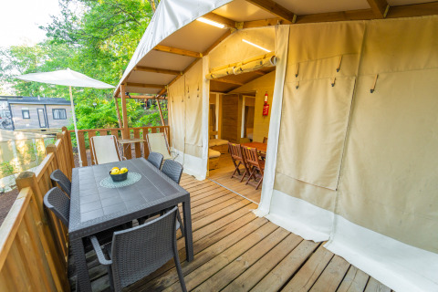 Terrasse mit Esstisch und Stühlen vor einem Lodge Tent Deluxe im Weekend Glamping Resort in Italien.