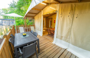 Terraza exterior con mesa de comedor y sillas junto a una Lodge Tent Deluxe en Weekend Glamping Resort, Italia.