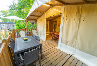 Terrasse mit Esstisch und Stühlen vor einem Lodge Tent Deluxe im Weekend Glamping Resort in Italien.