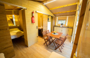 Indvendig udsigt over Lodge Tent Deluxe på Weekend Glamping Resort i Italien med spisebord og køkken.