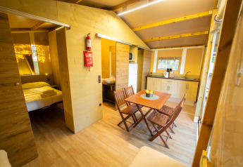 Vista interna della Lodge Tent Deluxe al Weekend Glamping Resort in Italia con zona pranzo e cucina.