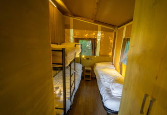 Interno della Lodge Tent Deluxe con letti a castello e singoli al Weekend Glamping Resort in Italia.
