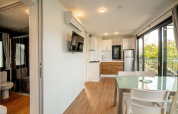Bright lodge interior with modern kitchen, living area, dining table, and nature views through large windows.