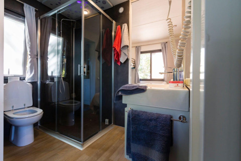 Salle de bains moderne avec douche, toilettes et lavabo au Next XL Panorama du Chianti Glamping Resort, Italie.