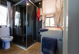 Salle de bains moderne avec douche, toilettes et lavabo au Next XL Panorama du Chianti Glamping Resort, Italie.