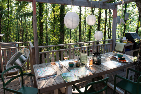 Buiten eethoek bij Bohemian Lodge in Chianti Glamping Resort, Italië, met lantaarns en bosrijk uitzicht.