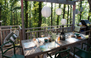 Essbereich im Freien bei der Bohemian Lodge im Chianti Glamping Resort, Italien, umgeben von Wald und Laternen.