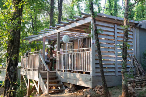 Houten terras van Bohemian Lodge bij Chianti Glamping Resort in Italië, omgeven door bomen en bos.