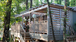 Terrasse der Bohemian Lodge im Chianti Glamping Resort, Italien, mit Menschen, umgeben von Bäumen.