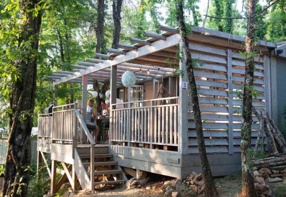 Houten terras van Bohemian Lodge bij Chianti Glamping Resort in Italië, omgeven door bomen en bos.
