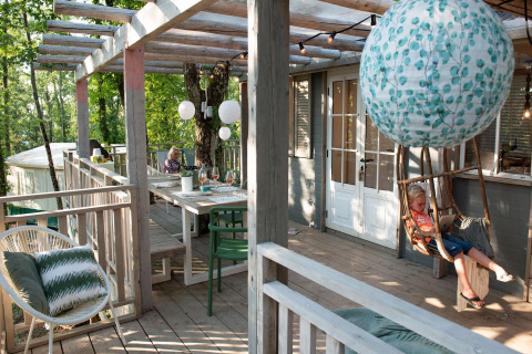 Buitenveranda bij Bohemian Lodge, Chianti Glamping Resort, Italië, met hangstoel en sfeervolle lantaarns.