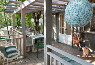 Buitenveranda bij Bohemian Lodge, Chianti Glamping Resort, Italië, met hangstoel en sfeervolle lantaarns.