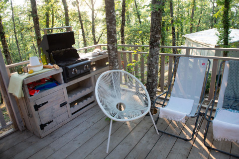 Buiten terras met barbecue, stoelen en boszicht bij Bohemian Lodge, Chianti Glamping Resort in Italië.