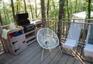 Buiten terras met barbecue, stoelen en boszicht bij Bohemian Lodge, Chianti Glamping Resort in Italië.